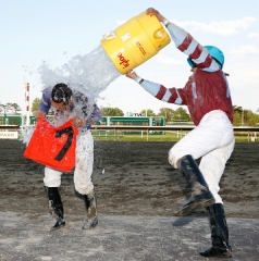 Jockey Paco Lopez (L) gets a cooler of ice water dumped on him by Jockey Gabriel Saez after Lopez scored a Monmouth Park record 7th win in a day in the last race at the Oceanport, New Jersey track aboard Tycoon Cat on Saturday May 17, 2014. Photo By William Osborn/EQUI-PHOTO